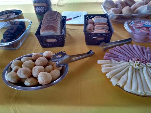 een tafel met verschillende soorten gebak en andere voedingsmiddelen bij Residencial Villa Nova in Boicucanga