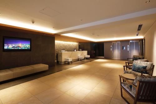 a lobby with a couch and a tv on a wall at HOTEL MYSTAYS Sapporo Susukino in Sapporo