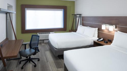 a hotel room with two beds and a desk and a chair at Holiday Inn Express & Suites Orlando At SeaWorld by IHG - With Free Shuttle Service to SeaWorld Parks in Orlando