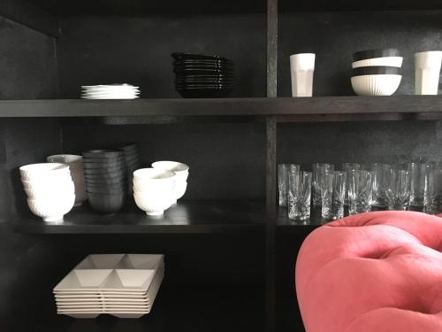a shelf with cups and plates and a red chair at Oasis Wadaura in Minamiboso
