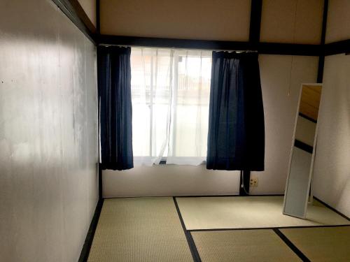 a room with a window with blue curtains at Oasis Wadaura in Minamiboso