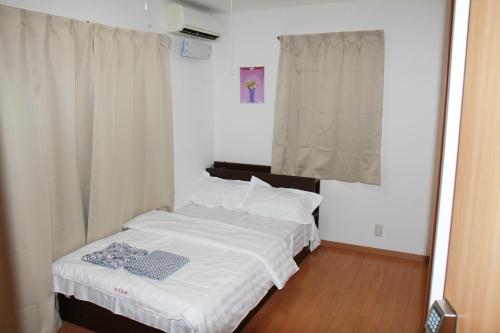 a bedroom with a bed with white sheets and a window at 近辺天然温泉5Ldkまるまる貸切日暮里駅まで直通 in Soka