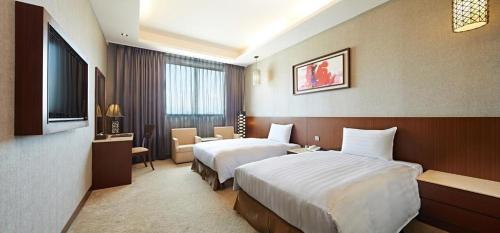 a hotel room with two beds and a television at Guanko Hotel in Chiayi City