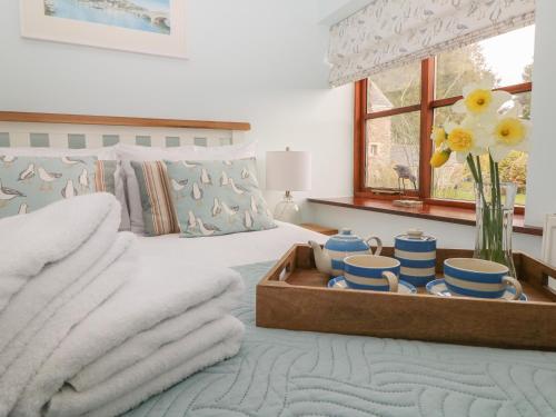 a bedroom with a bed with a tray of dishes at Erin Cottage in Pelynt