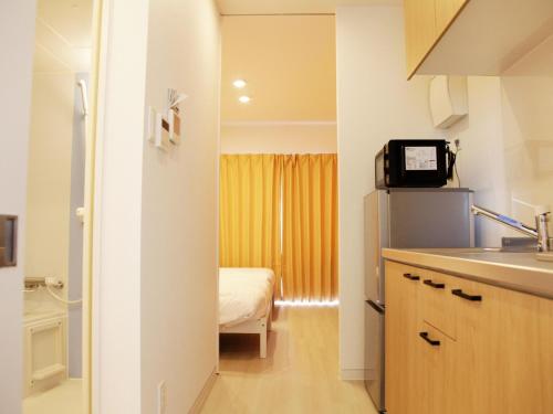 una cocina con fregadero y una cama en una habitación en Mango Resort Okinawa Naha en Naha