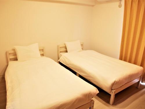 2 camas en una habitación pequeña con sábanas blancas en Mango Resort Okinawa Naha en Naha