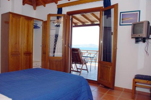 a bedroom with a bed and a tv and a balcony at Vila Elena 2 astoning view in Steni Vala Alonissos