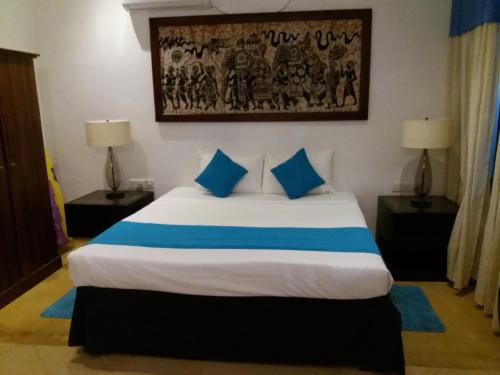 a bedroom with a large bed with blue pillows at Sujeewani Villa in Negombo