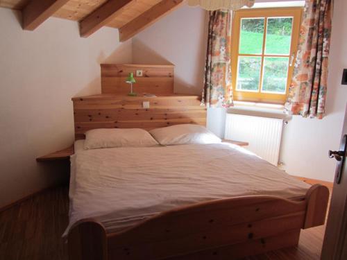 a bedroom with a large wooden bed with a window at Appartements Lindenhof in Vandoies