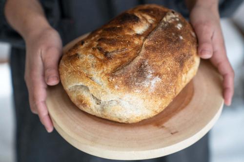 a person holding a plate with a loaf of bread at Onpoint Madarao in Myoko