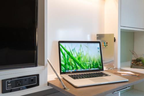 a laptop computer sitting on a desk next to a tv at EVEN Hotel Rockville - Washington, DC Area by IHG in Rockville