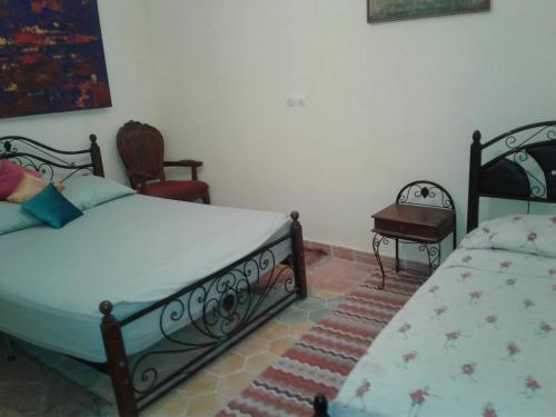 1 dormitorio con 2 camas, mesa y sillas en Maison d hôtes a Tioute Chez Abdelmajid en Tiout