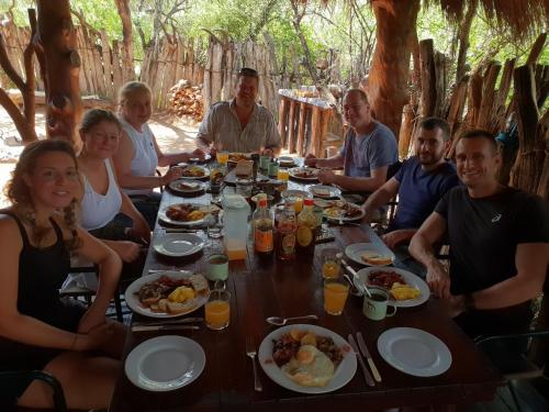 a group of people sitting around a table eating food at Quatermain's 1920's Safari Camp – Amakhala Game Reserve in Amakhala Game Reserve