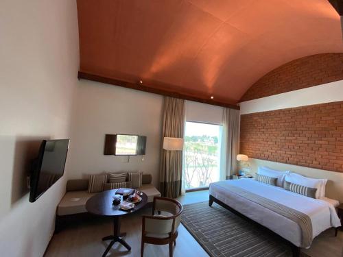 a bedroom with a bed and a table and a tv at Marasa Sarovar Premiere, Bodhgaya in Bodh Gaya
