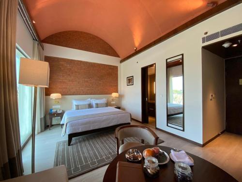 a hotel room with a bed and a table and a room at Marasa Sarovar Premiere, Bodhgaya in Bodh Gaya