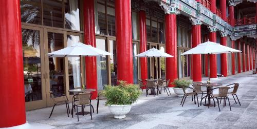 a row of tables and chairs with umbrellas on a street at The Grand Hotel Kaohsiung in Kaohsiung