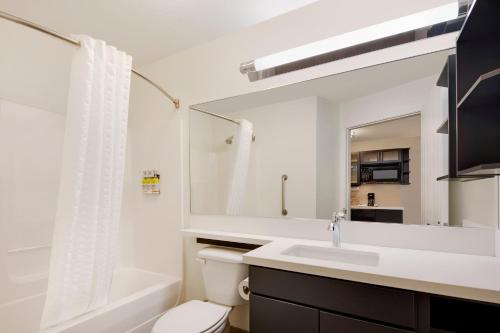 een badkamer met een wastafel, een toilet en een spiegel bij Candlewood Suites Rogers-Bentonville, an IHG Hotel in Rogers