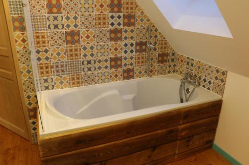 y baño con bañera y pared de azulejos. en Chaumière d'Albâtre -Gîte-Détente nature et bien être, en Ourville-en-Caux