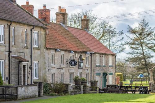 an old stone building with a clock on it at The Royal Oak in Gillamoor