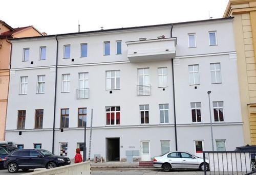 ein großes weißes Gebäude mit davor geparkt in der Unterkunft Apartman Oasis in Žilina