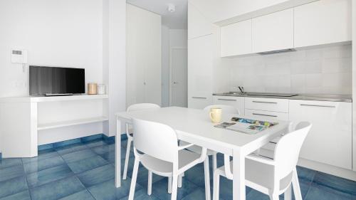 a white kitchen with a white table and chairs at Rivazzurra Homes - B in Termoli