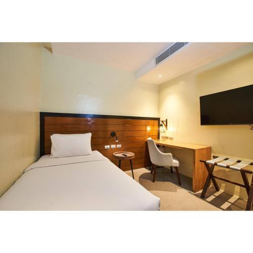 a bedroom with a bed and a desk and a television at Summit Galleria Cebu in Cebu City