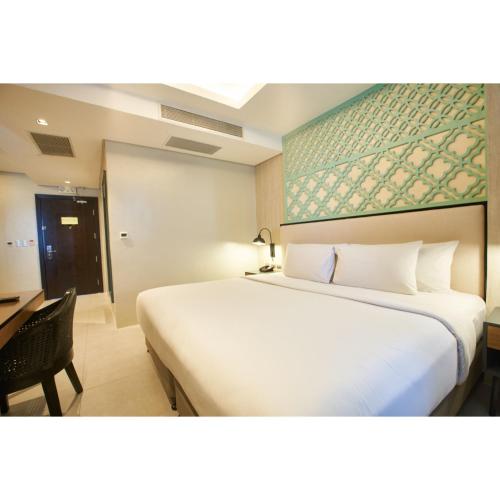 a hotel room with a large bed and a desk at Summit Galleria Cebu in Cebu City