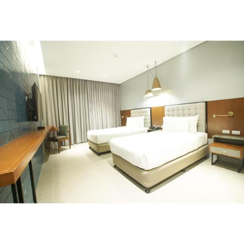 a hotel room with two beds and a desk at Summit Galleria Cebu in Cebu City