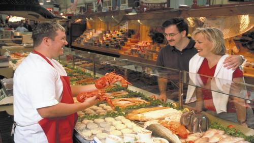 a man and woman standing in front of a buffet of food at Holiday Inn Express Hotel & Suites Saint John Harbour Side by IHG in Saint John