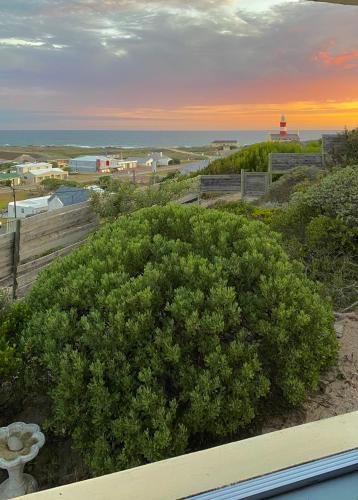 a view of a beach with a lighthouse and a bush at Agulhasbestview in Agulhas
