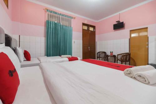 a bedroom with two beds with red and white at RedDoorz Plus @ Jalan Gatot Subroto Medan in Sunggal