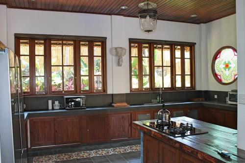 eine Küche mit Holzschränken und einer Arbeitsplatte in der Unterkunft Villa Bukit Malas 4, 4 Bedroom Villa and Pool in Ambat