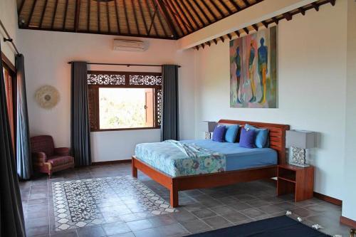 Schlafzimmer mit einem Bett und einem Fenster in der Unterkunft Villa Bukit Malas 4, 4 Bedroom Villa and Pool in Ambat