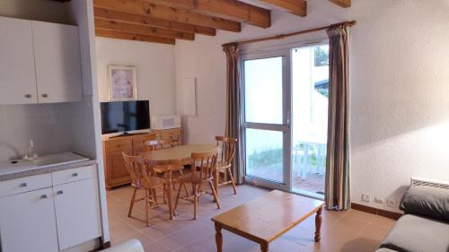 a living room with a table and a kitchen with a window at Réf 272,Seignosse océan, Villa Patio à 150m de la plage, avec place de parking et piscine commune , 4 personnes in Seignosse