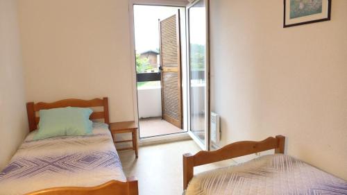 two beds in a room with a door to a balcony at Réf 272,Seignosse océan, Villa Patio à 150m de la plage, avec place de parking et piscine commune , 4 personnes in Seignosse