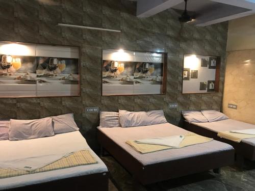 een kamer met drie bedden en een muur met foto's bij Hotel Rehoboth in Kanyakumari