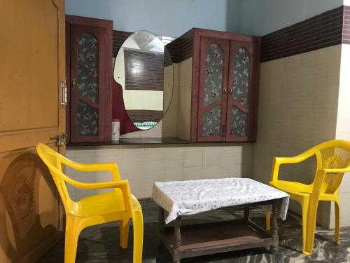 twee gele stoelen en een tafel en een spiegel bij Hotel Rehoboth in Kanyakumari
