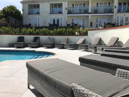 a pool with lounge chairs next to a building at La Barbarie Hotel in St Martin Guernsey
