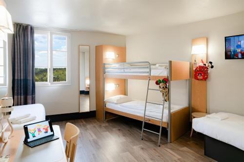 Cette chambre comprend 2 lits superposés et un bureau avec un ordinateur portable. dans l'établissement B&B Hôtel près de Disneyland Paris, à Magny-le-Hongre
