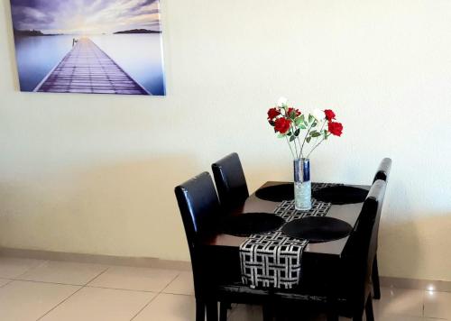 a dining room table with a vase of flowers on it at Ann's Place in Umdloti