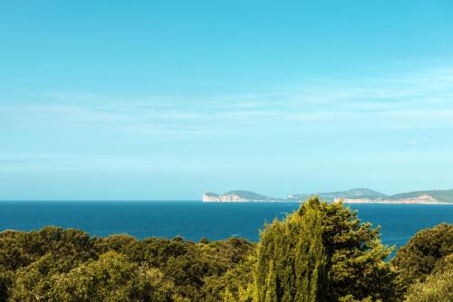 a view of the ocean with trees in the foreground at Villa Lucia in Alghero