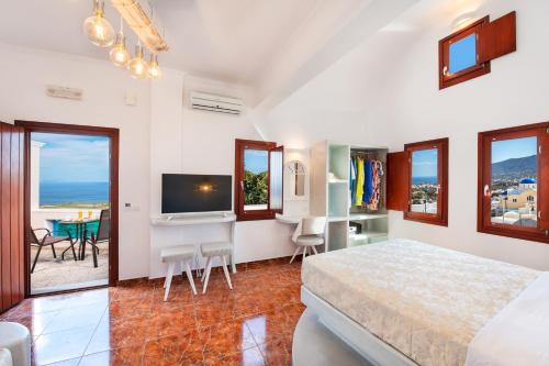 Schlafzimmer mit einem Bett, einem TV und einem Tisch in der Unterkunft Nectarios Villa - Studios & Suites Adults Only in Fira