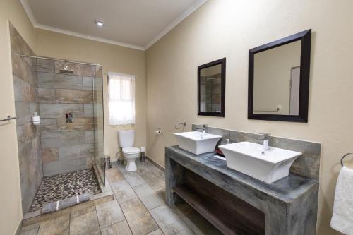 a bathroom with two sinks and a shower at The Belgium Inn in Hoedspruit