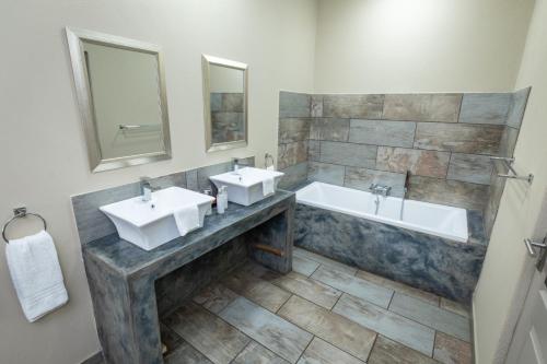 a bathroom with two sinks and a bath tub at The Belgium Inn in Hoedspruit