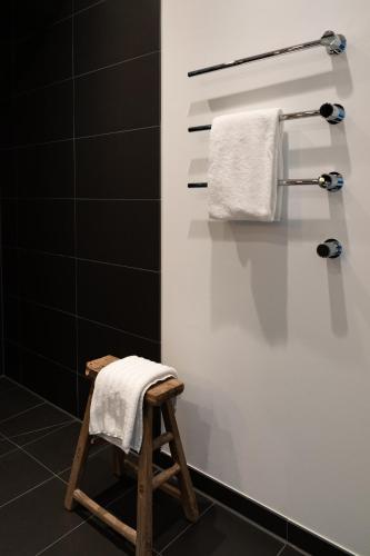 a bathroom with white towels and a wooden stool at Timehouse Serviced Apartments in Munich