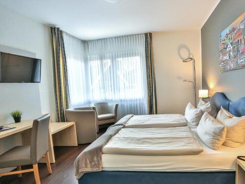 a hotel room with a bed and a desk at Hotel-Restaurant Kolpinghaus in Lingen