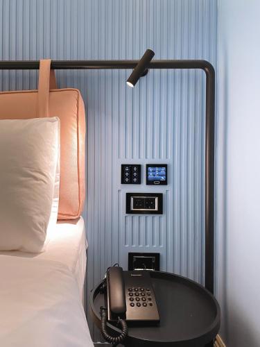 a bed with a phone on a table next to a bed at Iliria Boutique Hotel in Tirana
