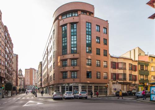 un edificio alto de ladrillo con coches estacionados frente a él en Hotel Gijon, en Gijón