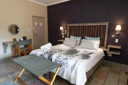 a bedroom with a large bed and a table at The Belgium Inn in Hoedspruit