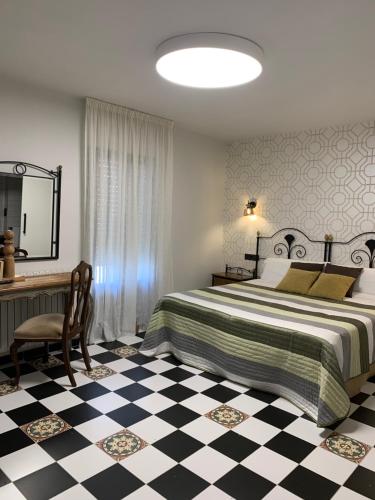 a bedroom with a large bed and a desk and a table at Hostal El Lechuguero in Cascante